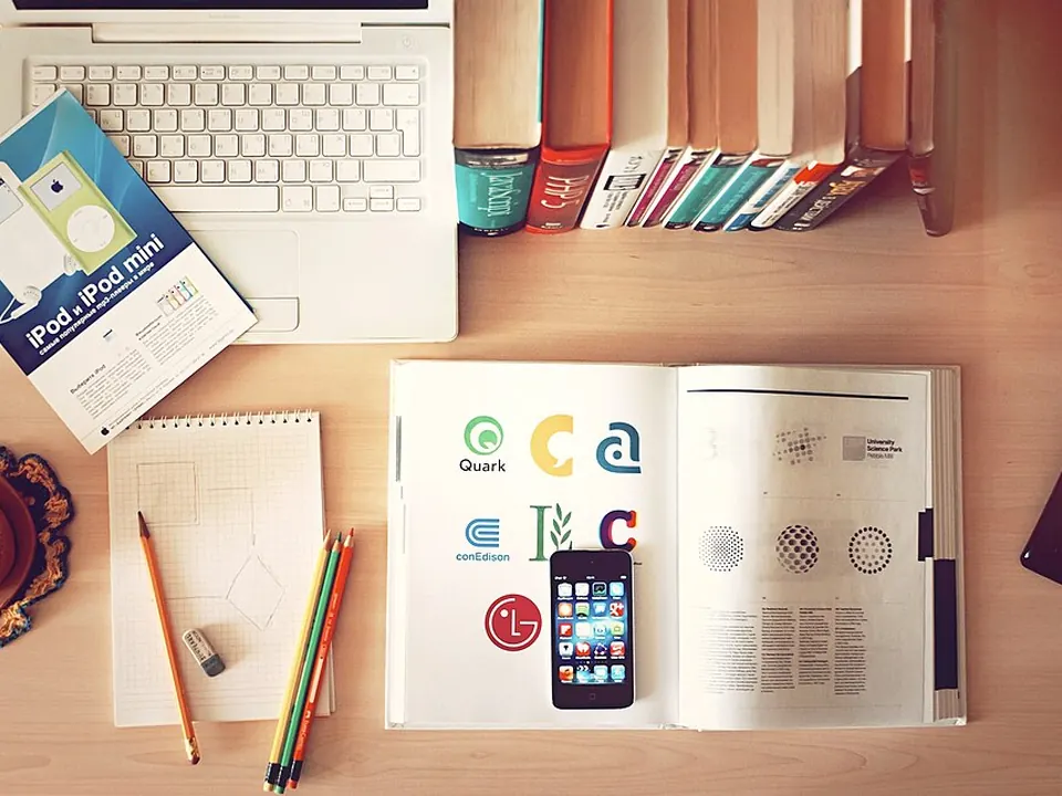 Books, pencils, phone, and laptop arranged on a desk
