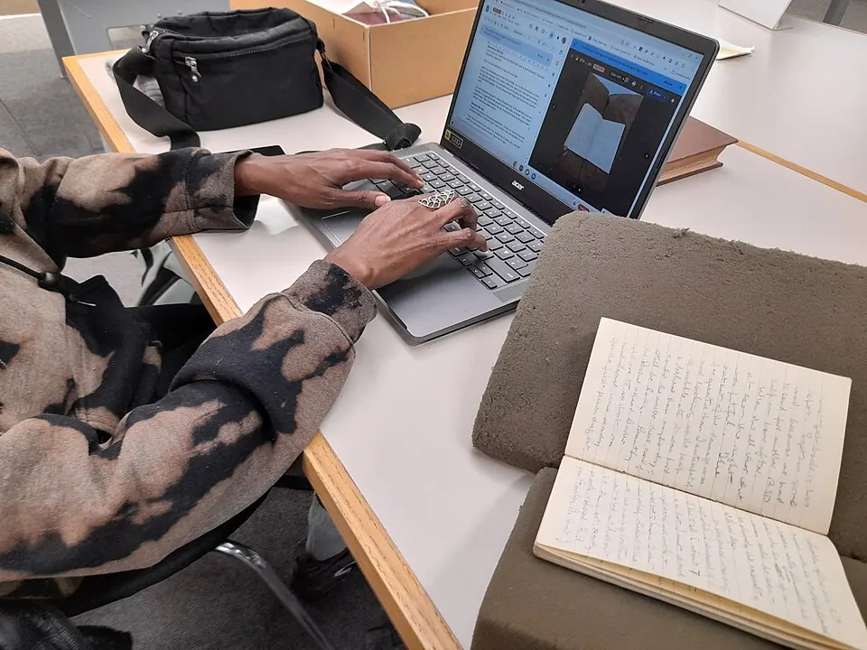 Volunteer using a laptop with documents spread across a desk