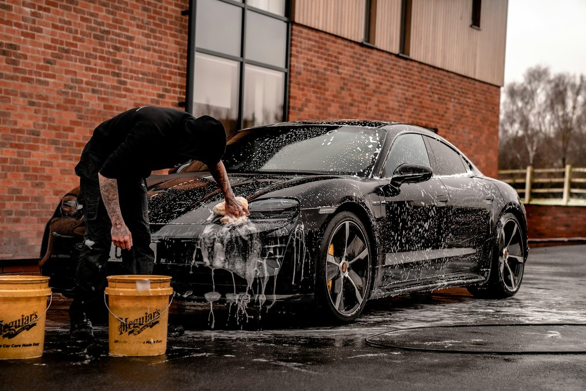A car being carefully hand-washed outside a detailing space